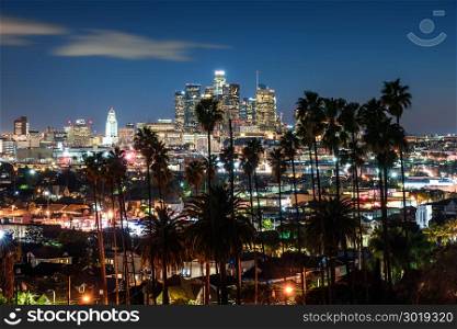 Beautiful night of Los Angeles downtown skyline and palm trees in foreground
