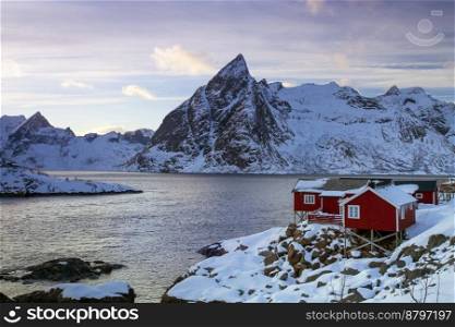 beautiful norwegian landscape - view of rorbu in the lofoten islands and snowy mountains in the background
