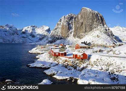 beautiful norwegian landscape - view of rorbu in the lofoten islands and snowy mountains in the background 