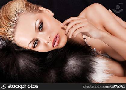 beautiful nude girl laying on black fur wearing with necklace