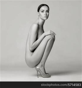 beautiful nude lady with perfect body sits in red shoes. Conceptual fashion art photo