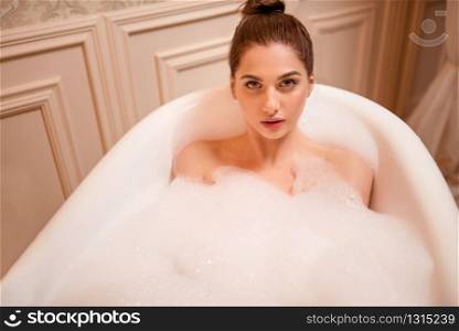 Beautiful nude woman in the bathtub with foam. Female relaxation in bathtub.