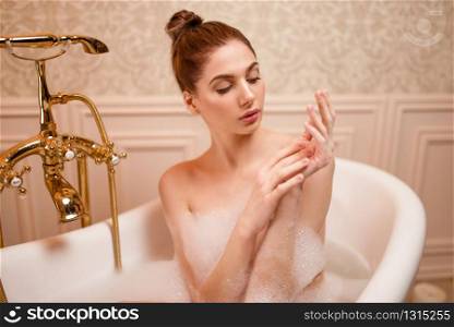 Beautiful nude woman resting in bathtub with soap.. Woman resting in bathtub