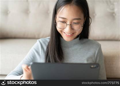Beautiful of asian woman touching keyboard on modern digital tablet, Asia girl smiling while working in her home