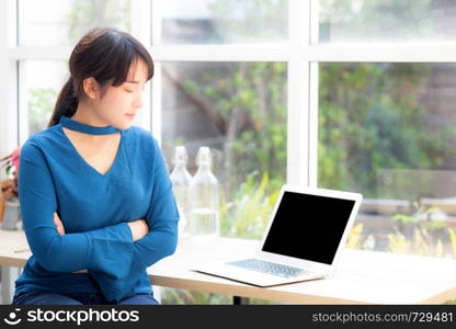 Beautiful of portrait asian young woman sitting looking camera and laptop on table at coffee shop, professional female freelance using notebook computer with connect to internet job.