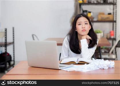 Beautiful of portrait asian young woman working online on laptop sitting and crumpled paper on table at coffee shop, professional female freelance using notebook computer, communication concept.