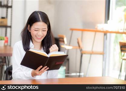 Beautiful of portrait business asian young woman reading on notebook with success on table, girl looking note excited at coffee shop, freelance and education concept.