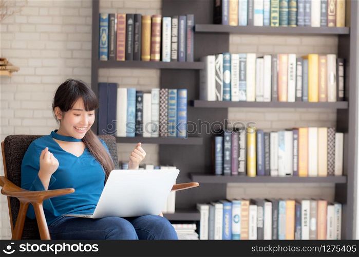 Beautiful of portrait happy young freelance asian woman using laptop work with success on chair in the home, asia girl and notebook shopping online with glad, communication concept.