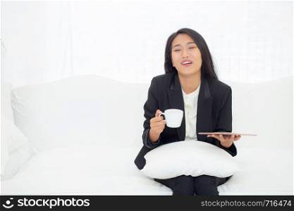 Beautiful of portrait young asian businesswoman sitting on sofa at home looking tablet computer and drinking coffee, woman ralex with internet, communication and business concept.