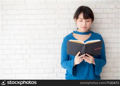 Beautiful of portrait young asian woman happiness relax standing reading book on concrete cement white background, girl happy study content literature, education and lifestyle concept.