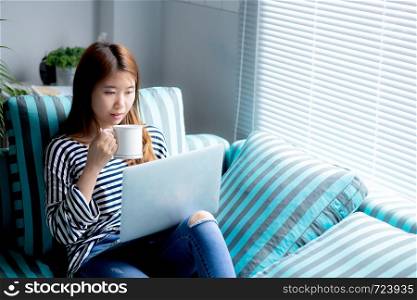 Beautiful of portrait young asian woman sitting use credit card with laptop and drink coffee, Content girl shopping online and payment with notebook computer on sofa, lifestyle concept.