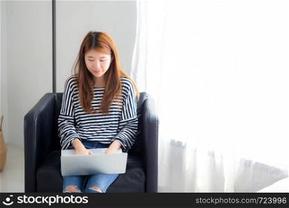 Beautiful of portrait young asian woman using laptop computer for leisure on chair at living room, girl working online with notebook freelance, communication business concept.