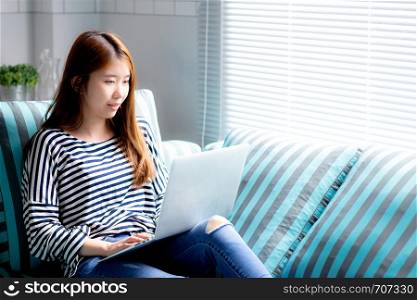 Beautiful of portrait young asian woman using laptop for leisure on sofa in living room, girl working online with notebook freelance with a happy, communication business concept.