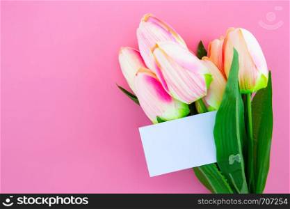 Beautiful of yellow tulip flower and card, note and tag with flat lay on the pink background, top view, copy space, mother day and holiday concept.