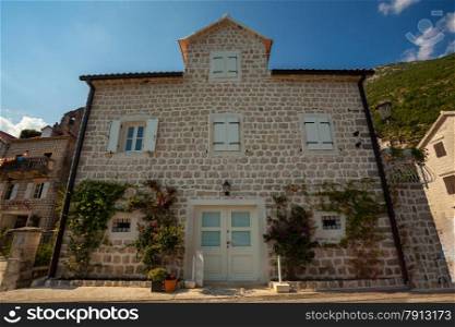 Beautiful old building with white wooden windows and doors in city of Perast