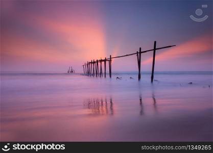 Beautiful old Wooden Bridge, wooden fisherman bridge. Beautiful of seascape Reflections from the sun at the sand, sunset at the sea southern of Thailand wooden bridge in pilai beach Phang Nga Thailand at Pilai beach, Phang Nga, Thailand.