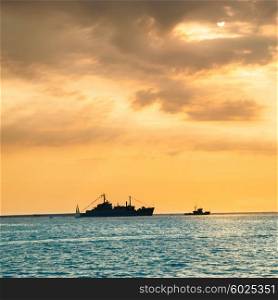 Beautiful orange sunset over blue sea with military war ship on the horizon