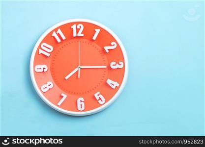 beautiful Orange wall clock on blue background ,concept of Start the morning to work.