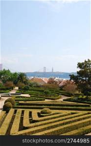 beautiful ornamental Ajuda garden with April 25th bridge on background in Lisbon, Portugal