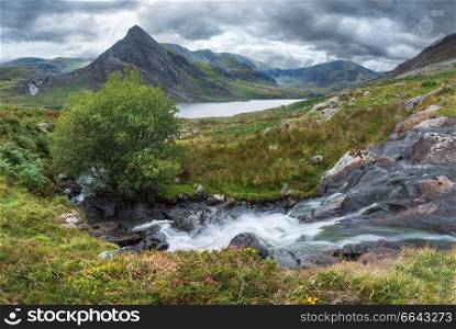 Beautiful panorama landscape image of stream flowing over rocks near Llyn Ogwen in Snowdonia during eary Autumn with Tryfan in background