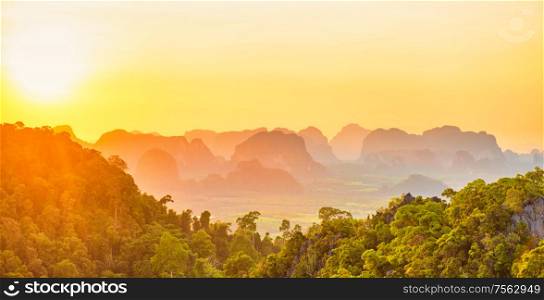 Beautiful panorama landscape with dramatic sunset, tropical rainforest and steep mountain ridge on horizon. Krabi, Thailand