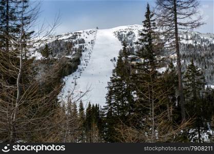 Beautiful panorama of big ski slope oh high mountain surrounded by spruces