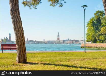 Beautiful park with green lawn, bench an view to city. Venice, Italy