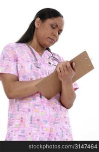 Beautiful pediactric nurse in pink scrubs writing on clipboard. Look of concentration on face.
