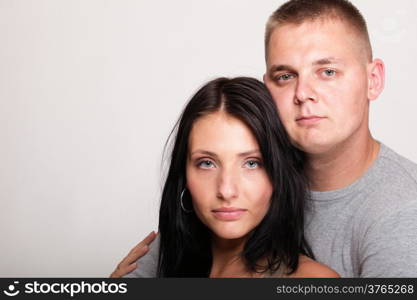 Beautiful pensive man and woman stand near gray wal