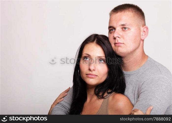 Beautiful pensive man and woman stand near gray wal