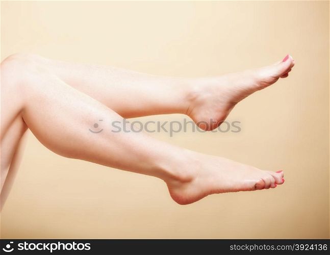 Beautiful perfect long naked woman girl legs barefoot body care pedicure on orange