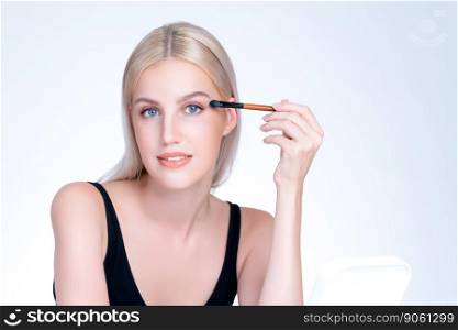 Beautiful personable girl with flawless applying eye shadow makeup with eyeliner brush. Cosmetic facial painting process on lovely young woman with perfect clean skin in isolated background.. Beautiful personable girl with flawless applying eye shadow makeup.