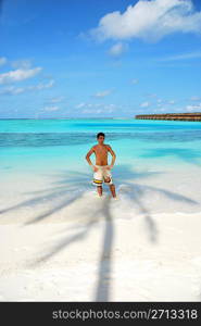 beautiful photo of a young adult standing in the shadow of a palm tree in Maldives