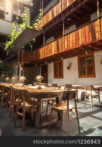 Beautiful photo of long wooden table and chairs in inner court of modern cafe. Beautiful image of long wooden table and chairs in inner court of modern cafe