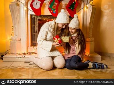 Beautiful photo of mother and daughter sitting at fireplace with Christmas gift