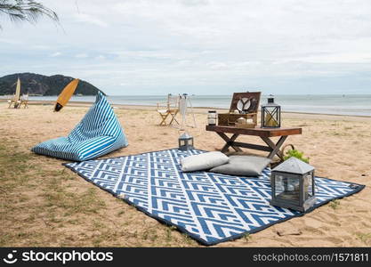 Beautiful picnic on beach in summer. mat, bean bag chair, surfboard on coast. Travel lifestyle and holiday vacation concept.