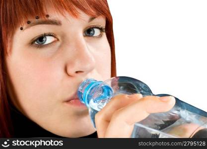 Beautiful pierced redhead girl drinking water from a bottle. Studio shot.