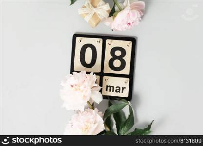Beautiful pink peony flowers and wooden calendar on white background. Concept Women’s Day, March 8. 8th march. Flat lay, top view