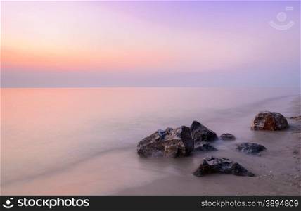 Beautiful pink sunrise at the beach with rock