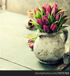 Beautiful pink tulips bouquet and garden tools on wooden table