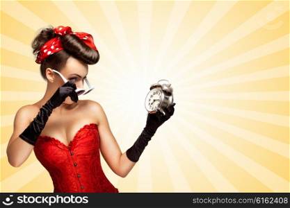 Beautiful pinup girl in a red vintage corset being late in the morning and holding a retro alarm clock in her hand on colorful abstract cartoon style background.