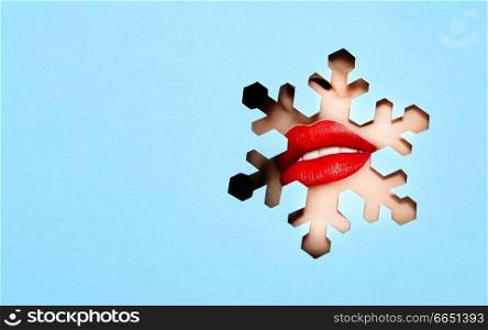 Beautiful Plump Bright Lips Of a Young Beautiful Woman with Red Lipstick Look Into the Pattern of Snowflakes made of Colored Paper. Snowflake. Christmas Patterns. Blue Paper