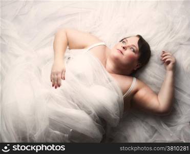 Beautiful plus size woman lying on the bed and looks towards to light.
