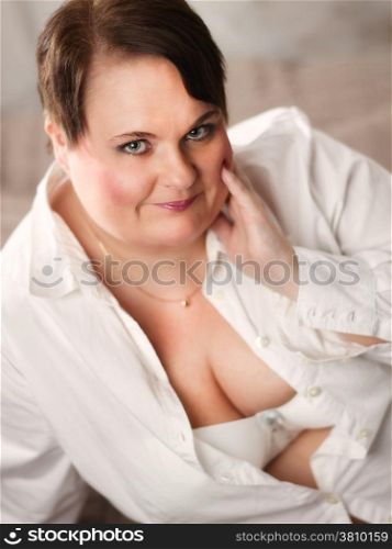 Beautiful plus size woman posing and looks in the camera, The woman is smiling in a happy manner.