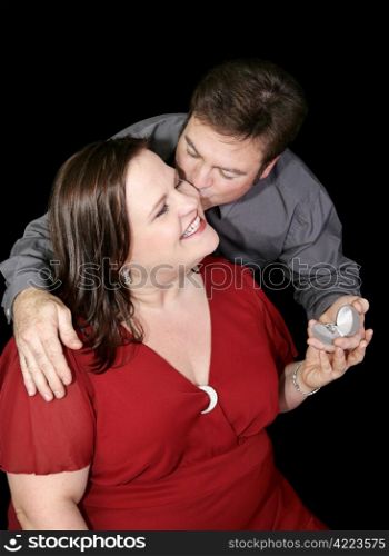 Beautiful plus sized model whose boyfriend is proposing to her. Black background.