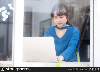 Beautiful portrait asia young woman working online on laptop sitting at cafe shop, professional female freelance using notebook computer, business and communication concept.