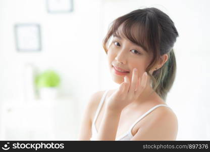 Beautiful portrait asian woman makeup of cosmetic, girl hand touch cheek and smile attractive, face beauty perfect with wellness in the bedroom with skin care and healthcare concept.