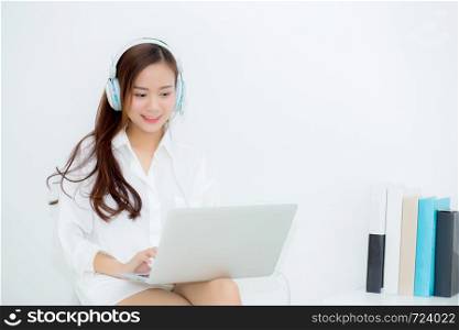 Beautiful portrait asian young woman happy enjoy and fun listen music with headphone and laptop computer sitting in living room, lifestyle of girl relax sound radio with earphone, leisure and technology concept.