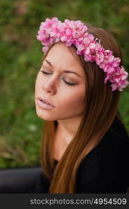 Beautiful portrait of a blonde girl with a pink crown of flowers on her head