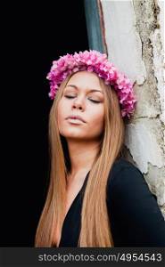 Beautiful portrait of a blonde girl with a pink crown of flowers on her head